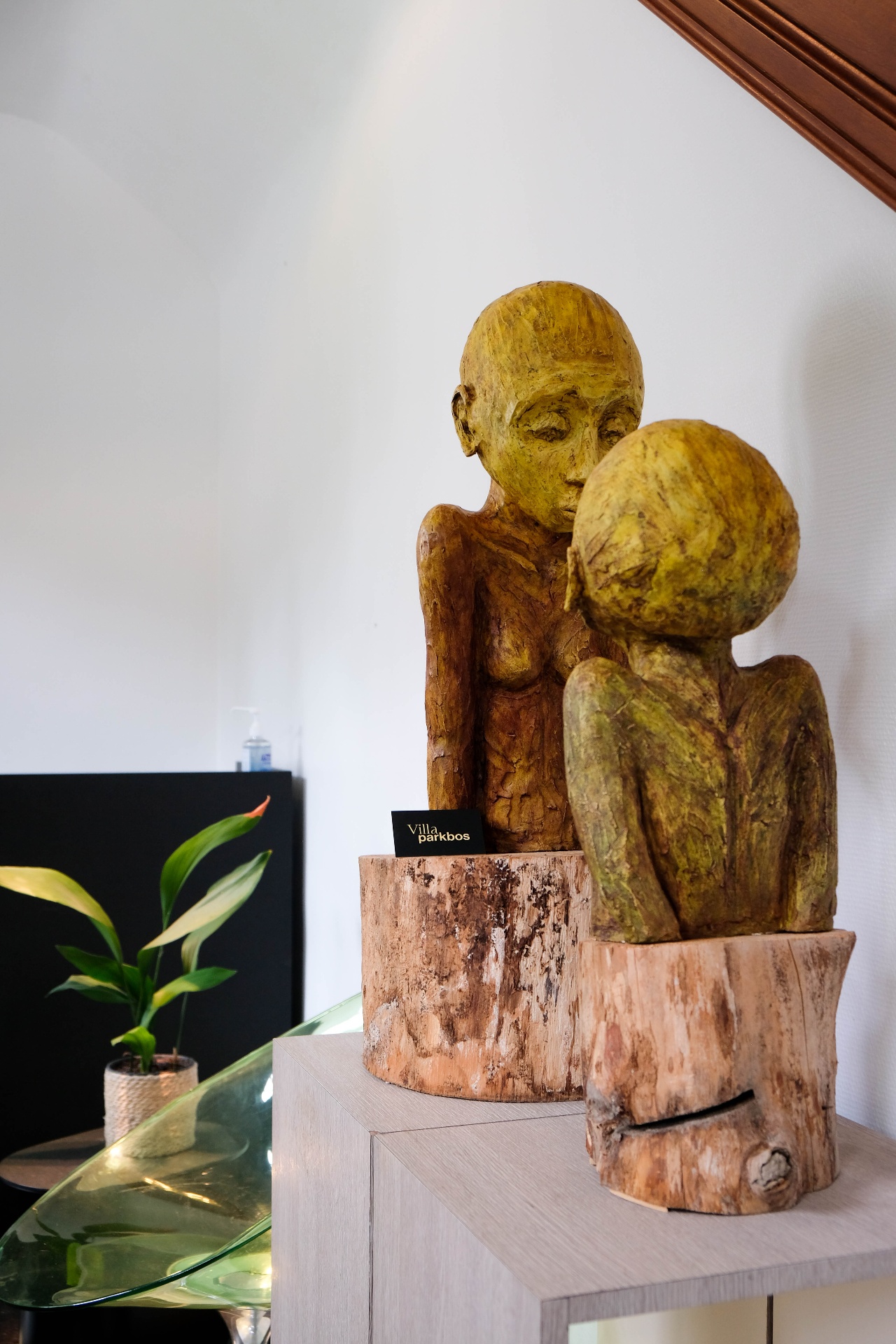 Houten sculpturen met Villa Parkbos-kaartje op een sidetable