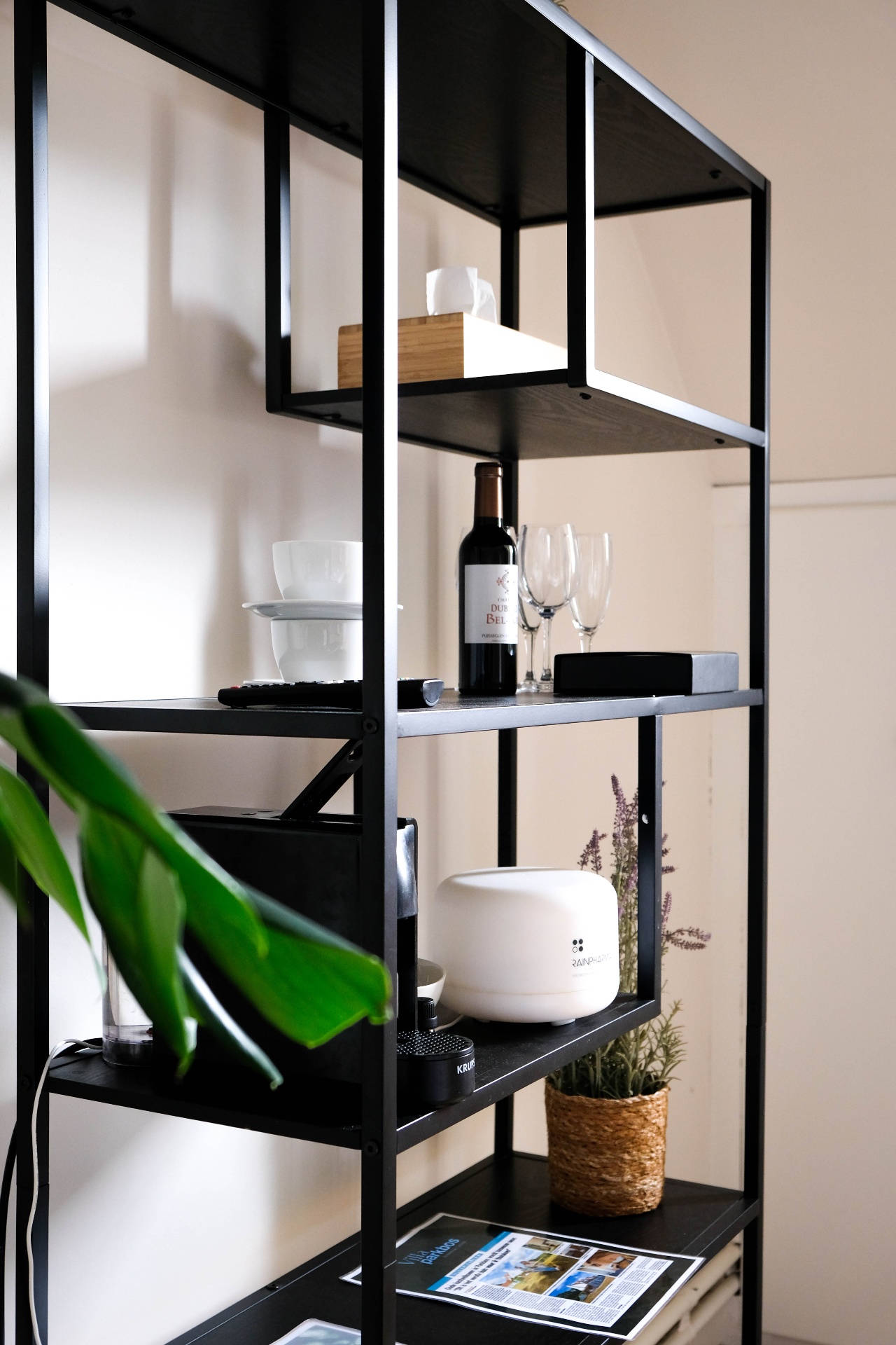 Zwart metalen rek met wijnglazen, koffiemachine en planten